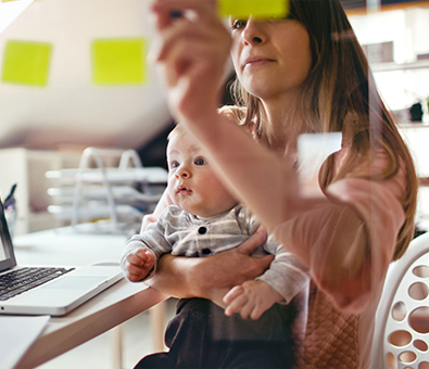 Mother holding baby and writing on post-it notes - Tulane SoPA