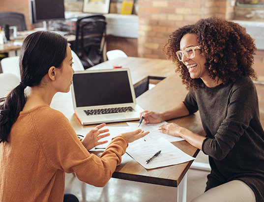 student and teacher talking at a desk - Tulane SoPA