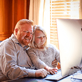 Father and daughter sitting at a computer desk - Tulane SoPA