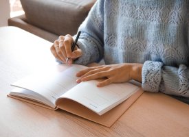 Person writing in notebook at a desk - Tulane School of Professional Advancement