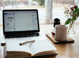 A notebook in front of a laptop on a desk