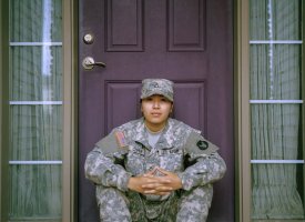 A woman in army cammies sitting in front of a door