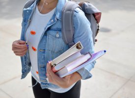 Transfer studen on university campus carrying books - Tulane School of Professional Advancement